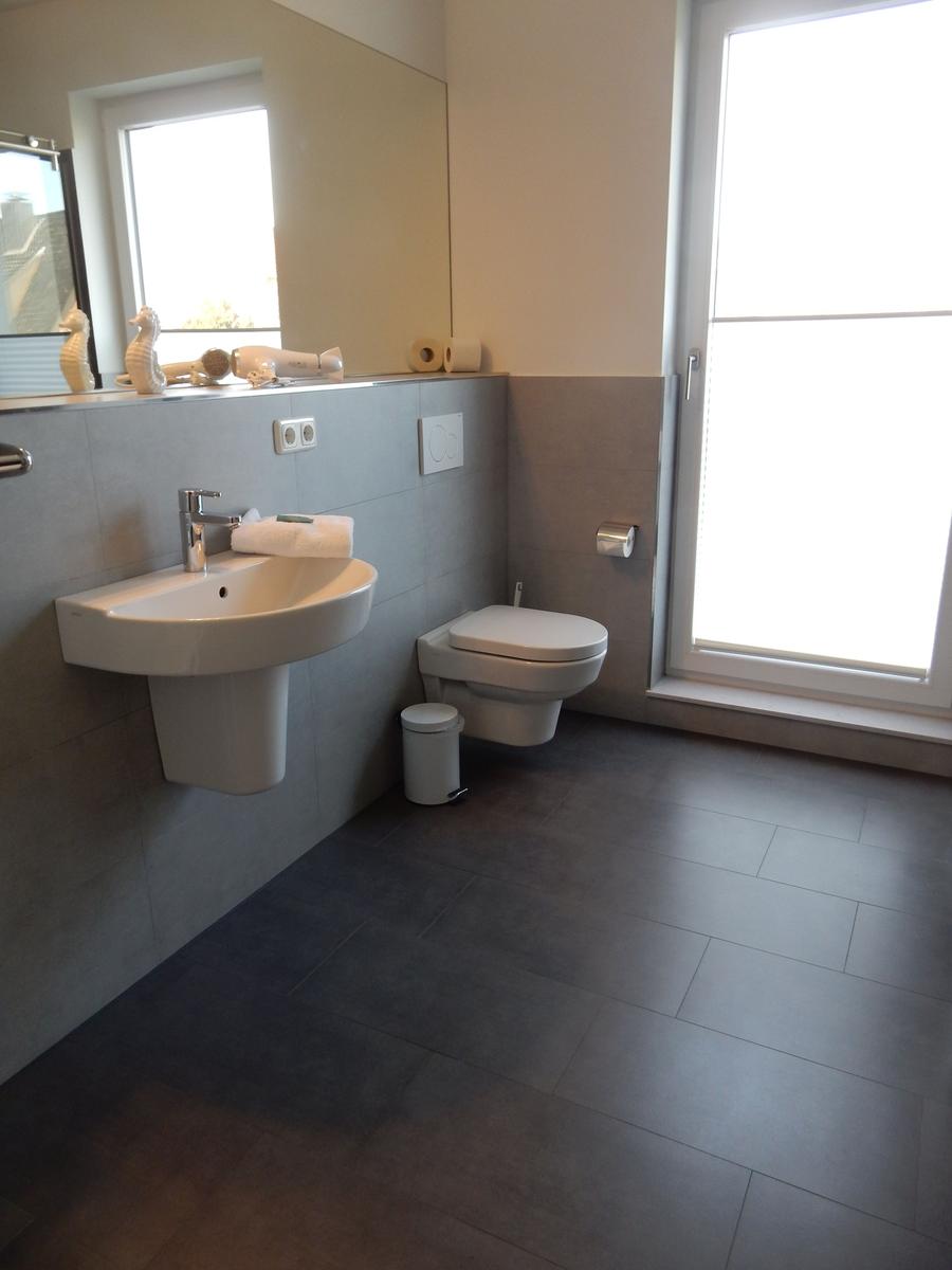 Badezimmer mit Waschbecken, WC und Fenster.