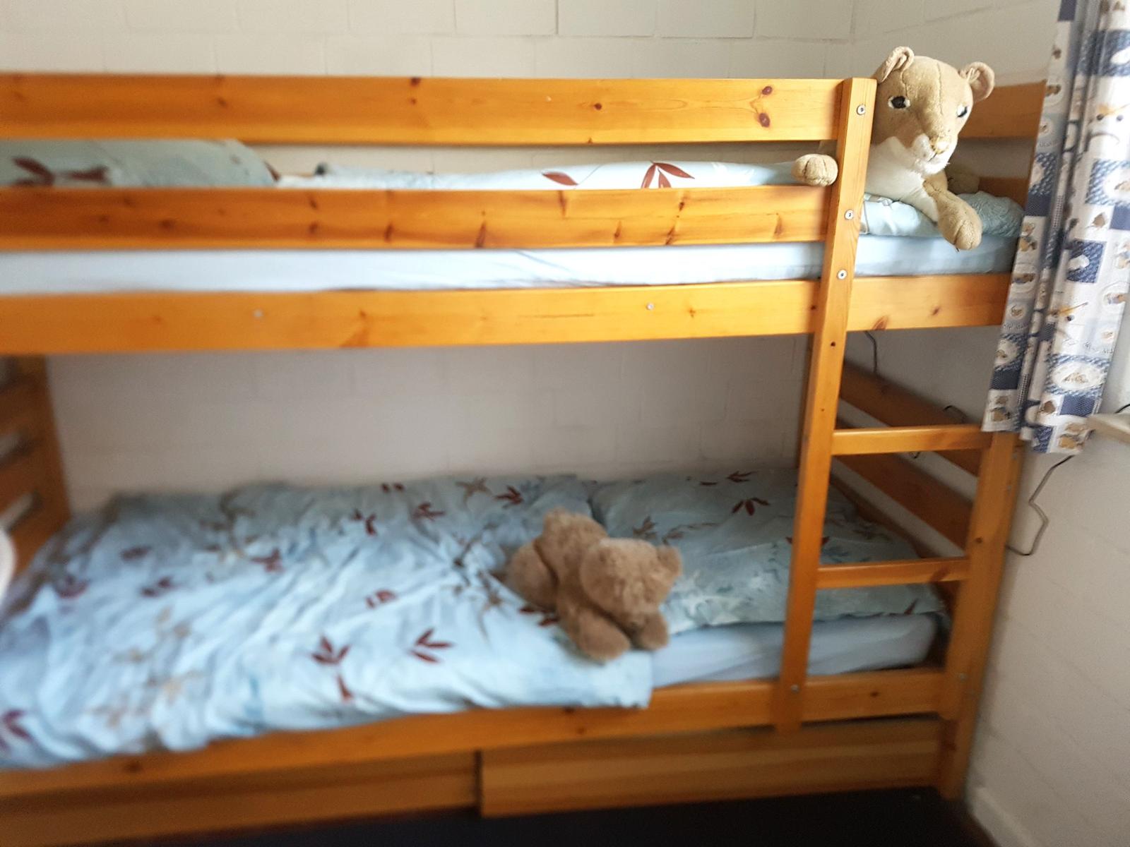 Ein Doppelstockbett mit zwei Matratzen und Kissen. Auf beiden Betten liegen Plüschtiere.