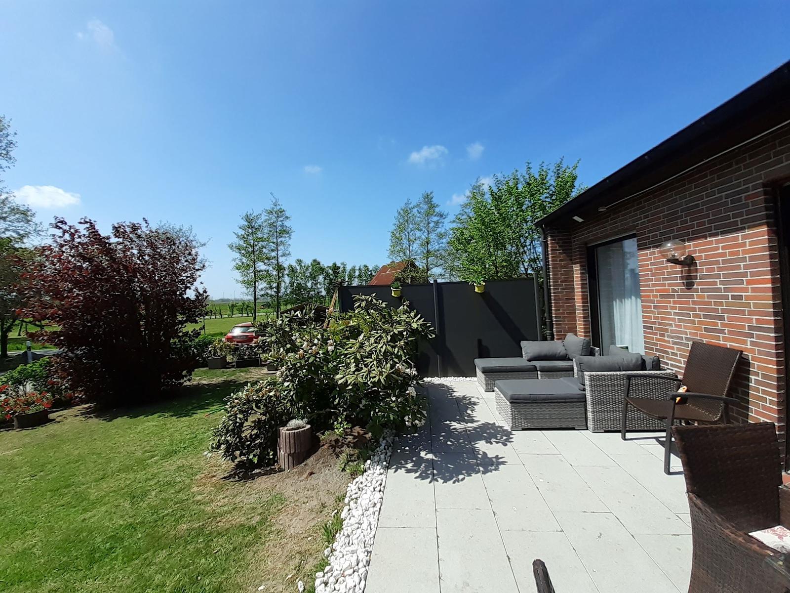 Terrasse mit Sitzgruppe, Garten und Blick auf Felder.