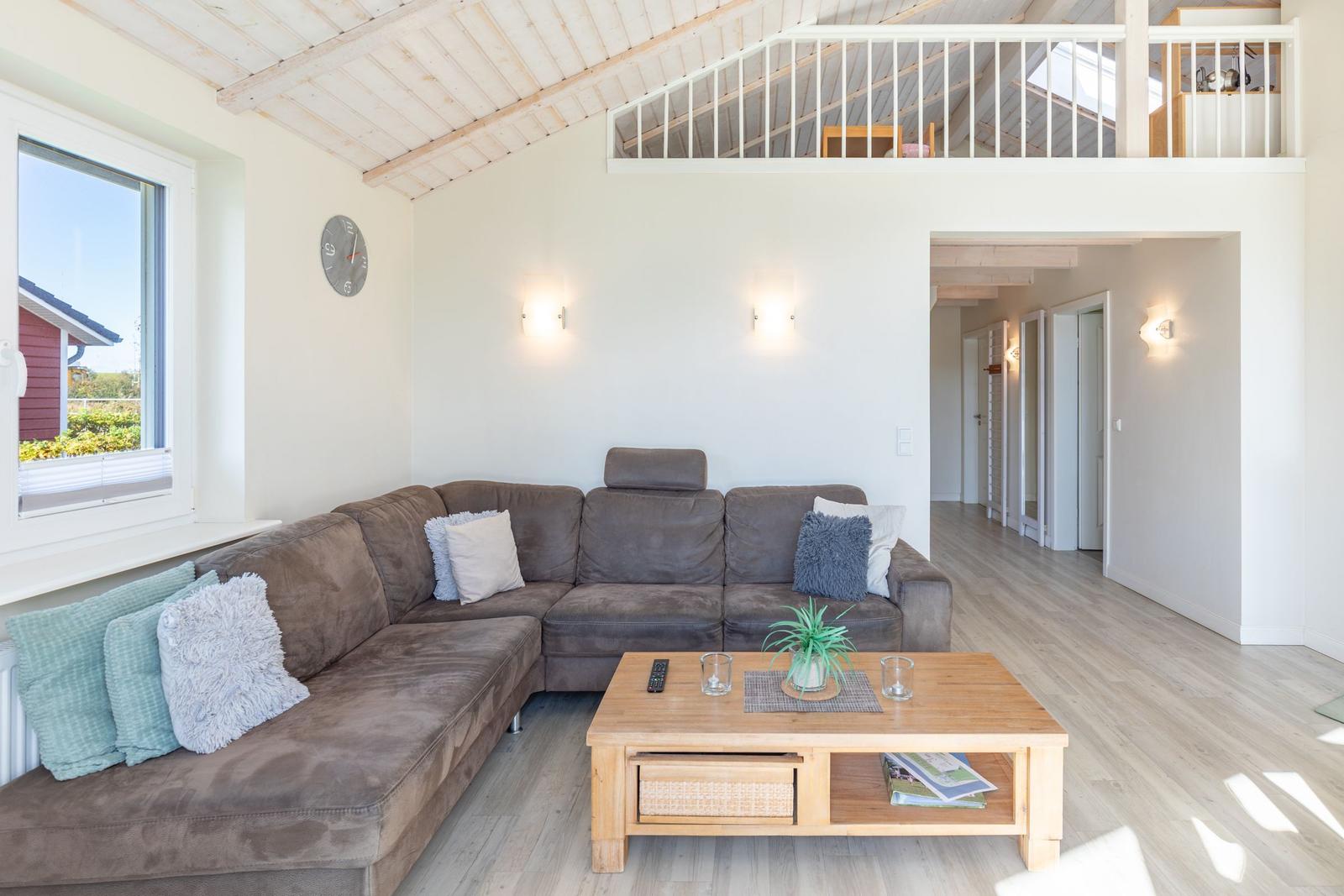 Wohnzimmer mit Sofa, Couchtisch und Balkon. Hölzerner Boden und weiße Wände.