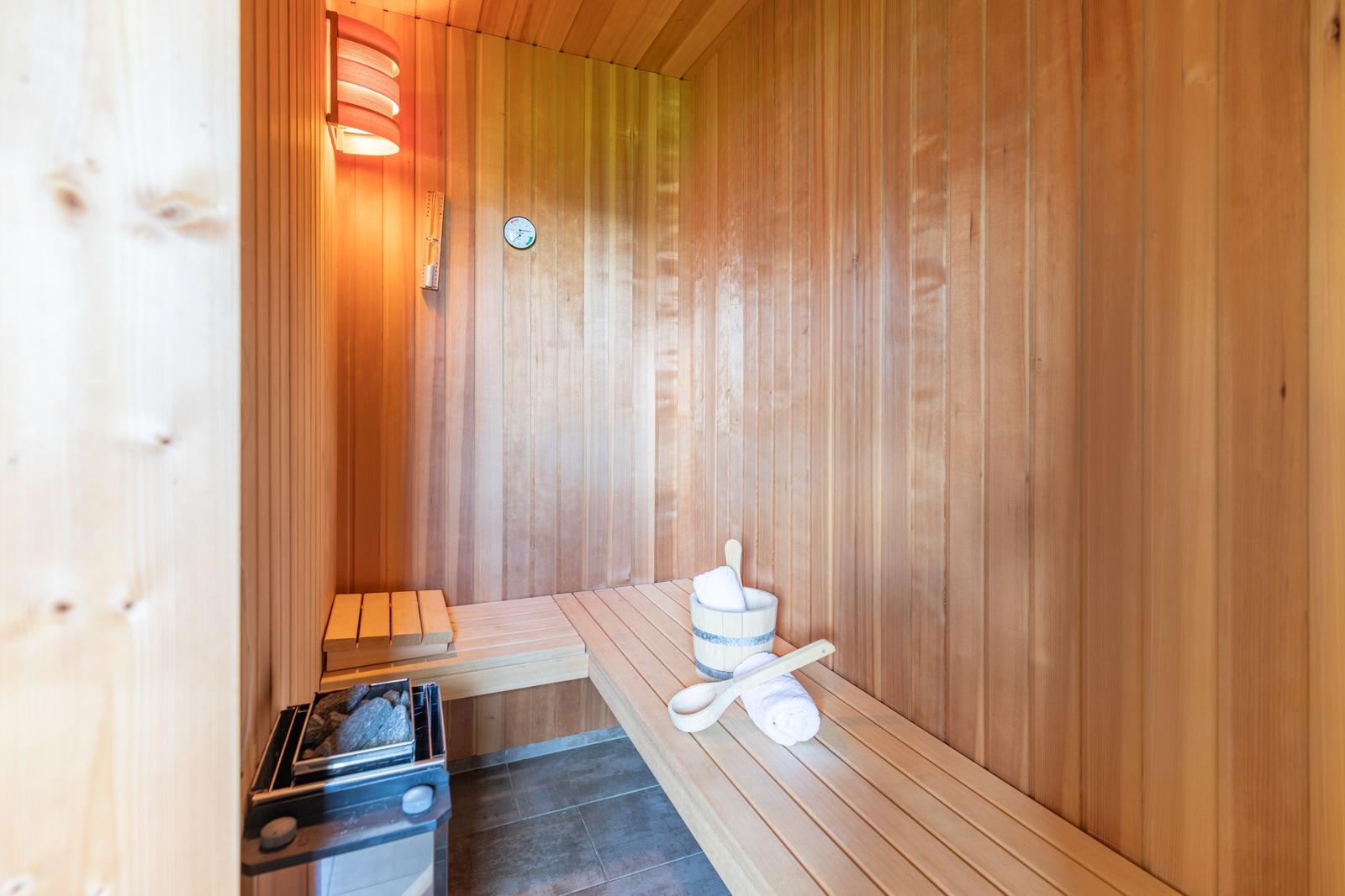 Sauna mit Holzwand, Bank, Steinkessel und Badematten.