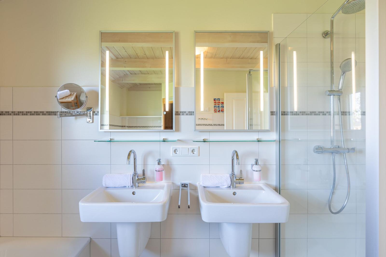Zwei Waschbecken mit Spiegeln und Dusche im Badezimmer.