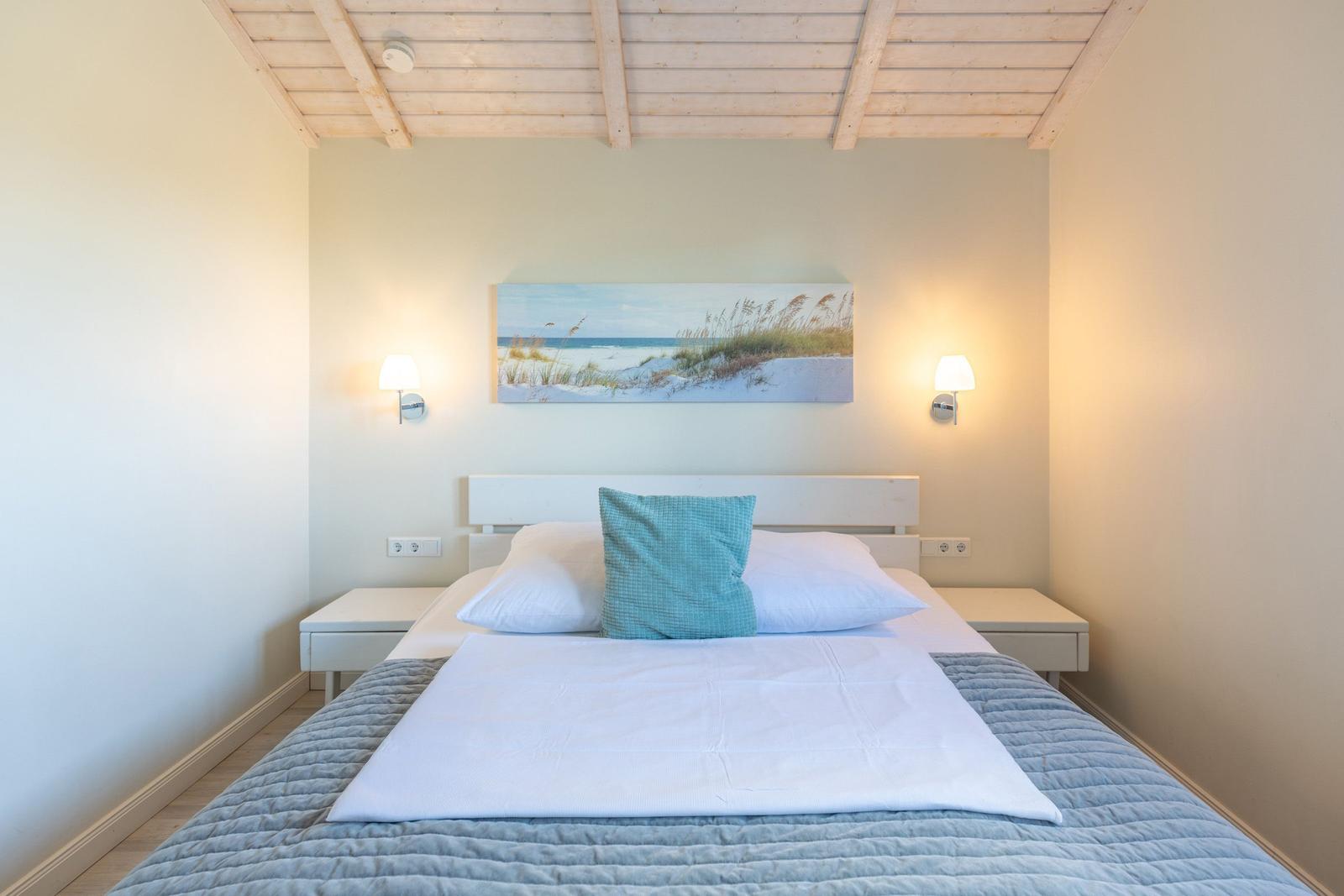 Schlafzimmer mit Bett, Wandbild und Stehlampe an den Wänden.