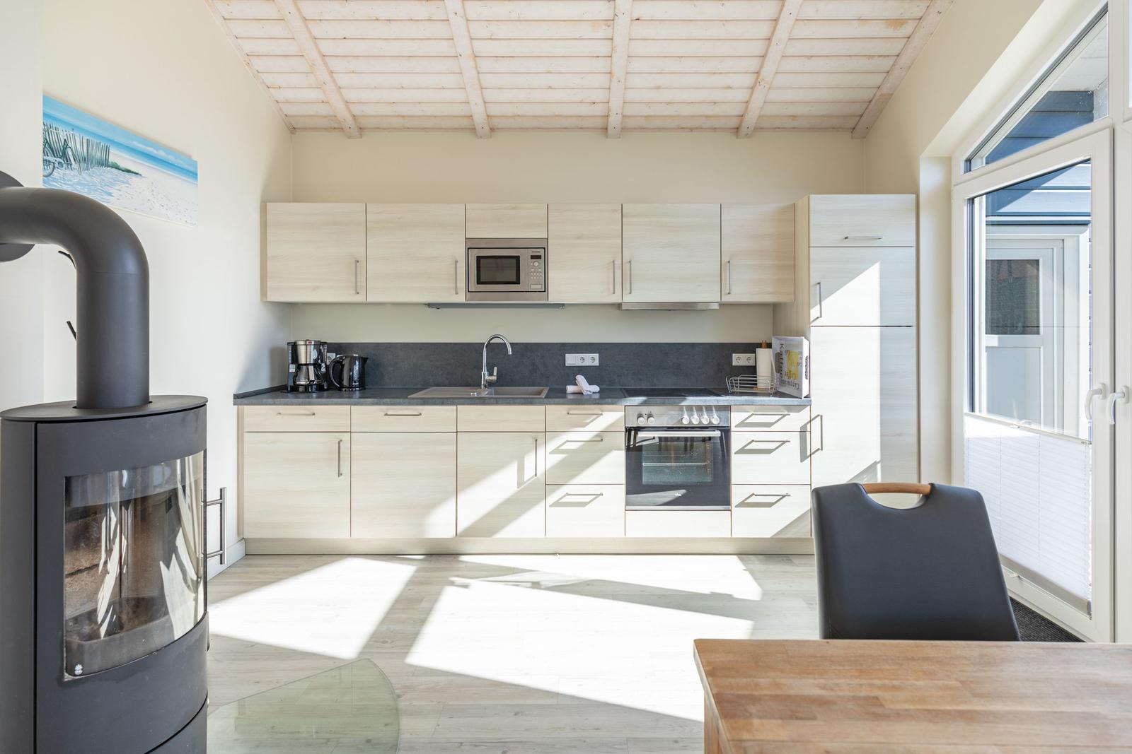 Küche mit Holzdecke, Kühlschrank, Herd und Mikrowelle.