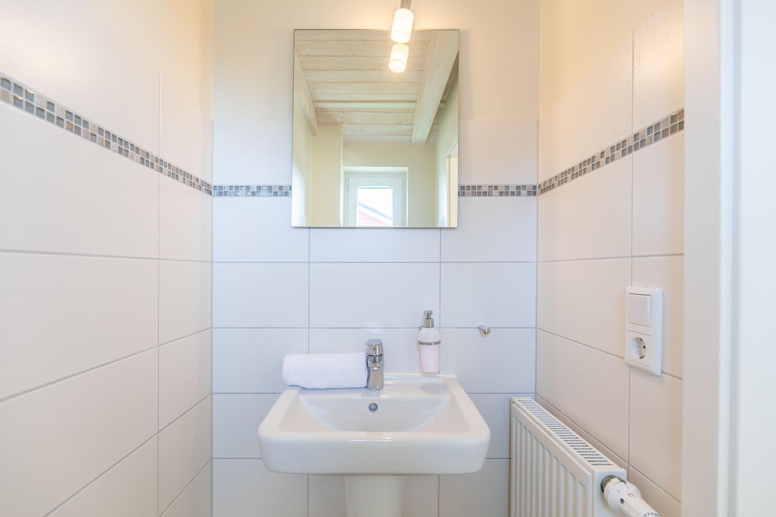 Badezimmer mit Waschbecken, Spiegel und Heizkörper an der Wand.