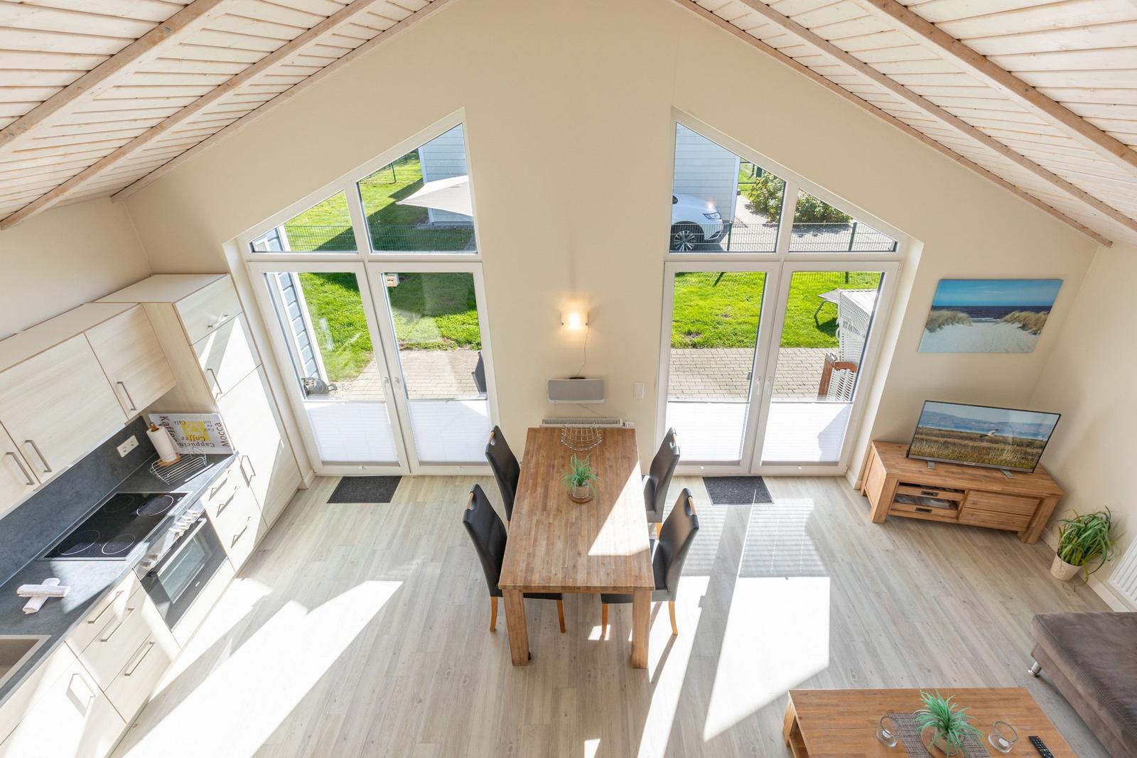 Küche, Essbereich und Wohnzimmer mit großen Fenstern und Holzboden.