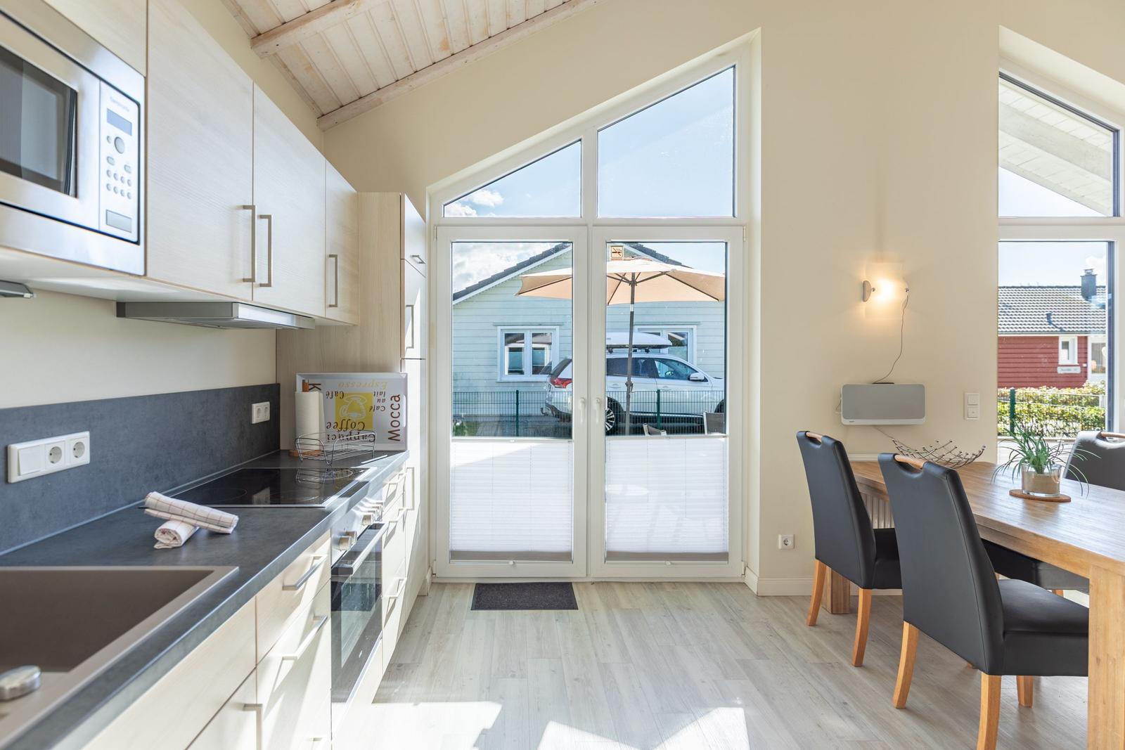 Küche mit Essbereich, großes Fenster und Balkonansicht.