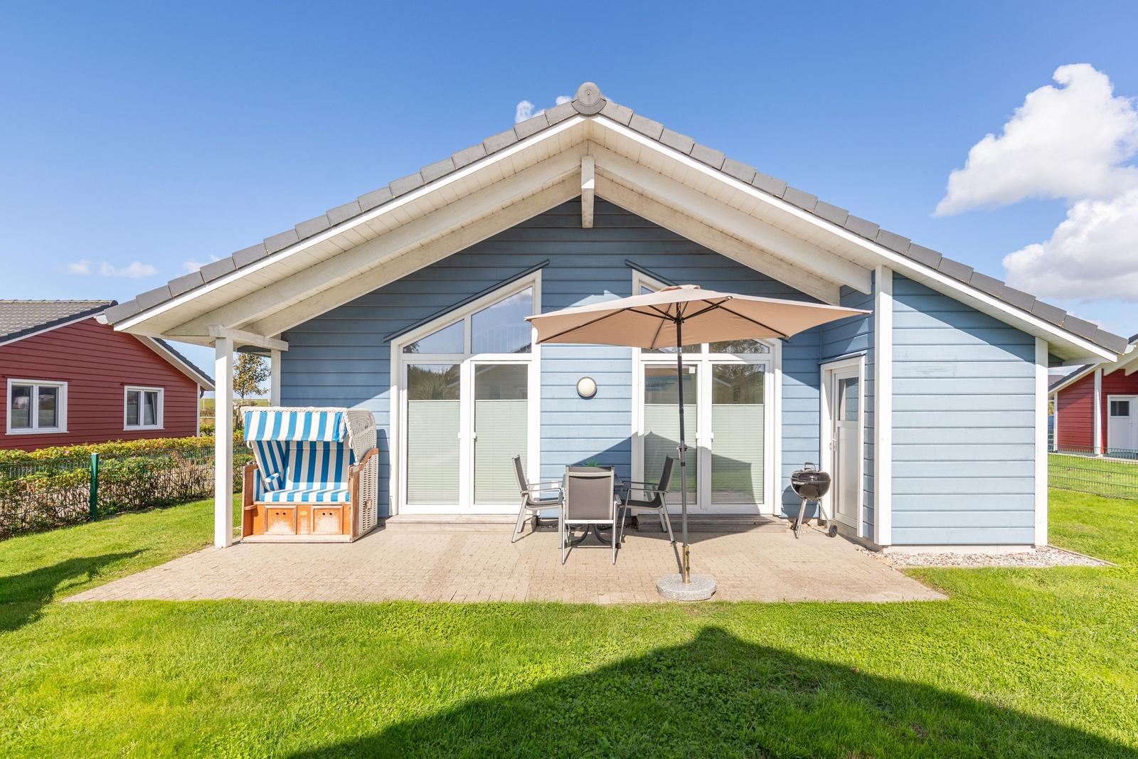 Blauer Ferienbau mit Terrasse, Strandkorb und Grill.