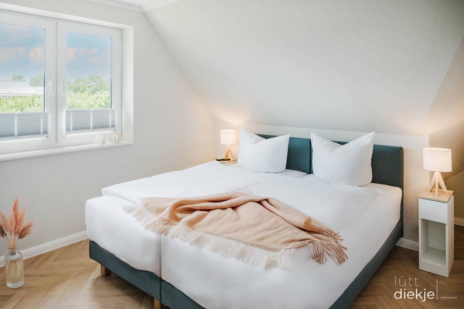 Schlafzimmer mit Doppelbett, Fenster und Nachttischen.