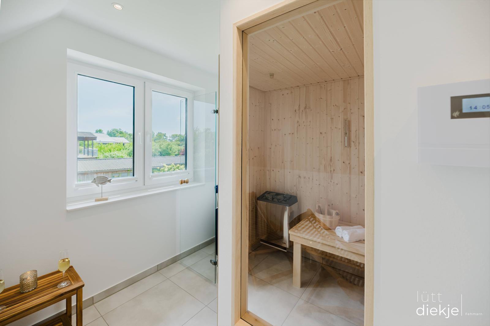 Sauna mit Holzwand und Bank. Fenster mit Blick auf Garten. Glaswand und Holztisch.