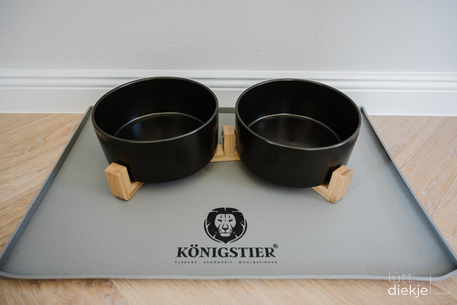 Zwei schwarze Futternäpfe auf einem grauen Untersetzer mit Markenlogo.