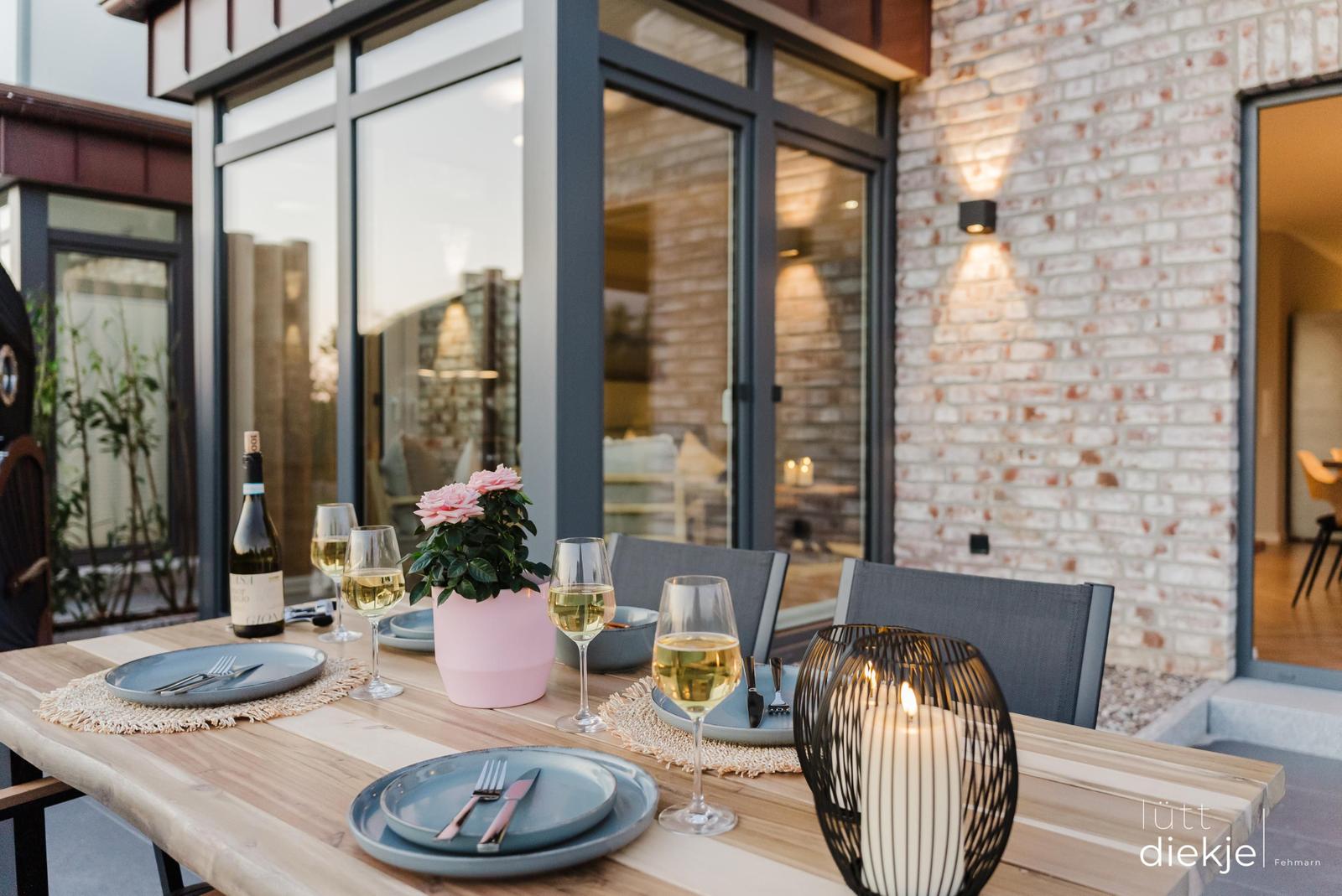 Terrasse mit gedecktem Tisch, Wein und Kerzen.