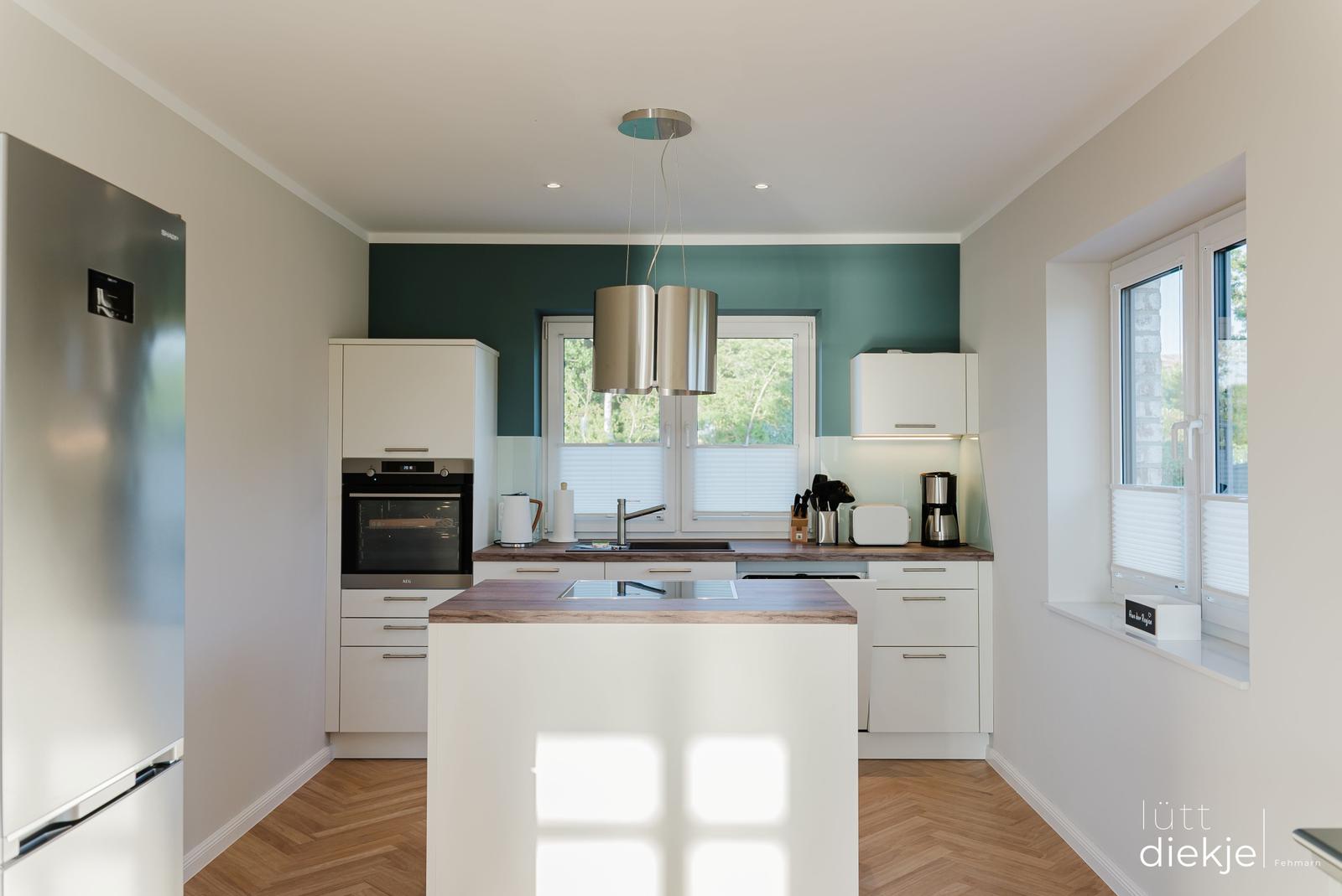 Moderne Küche mit Insel, weißen Schränken und Holzboden.