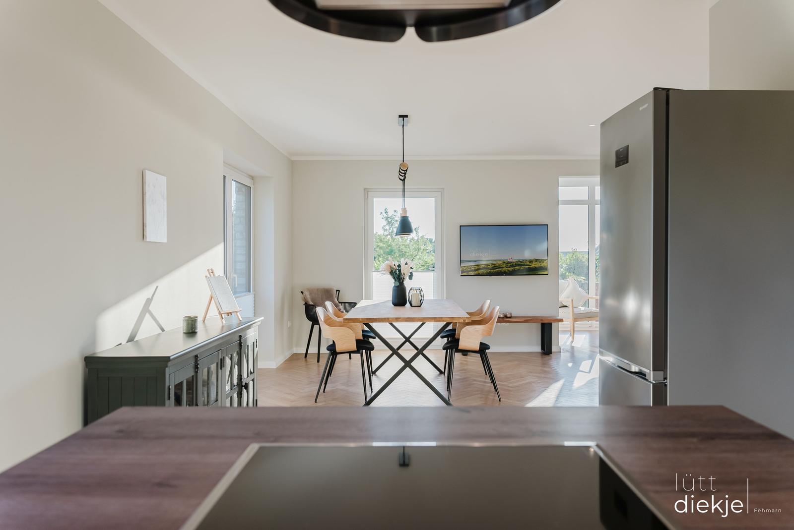 Esszimmer mit Holztisch, Stühlen und Küchenzeile