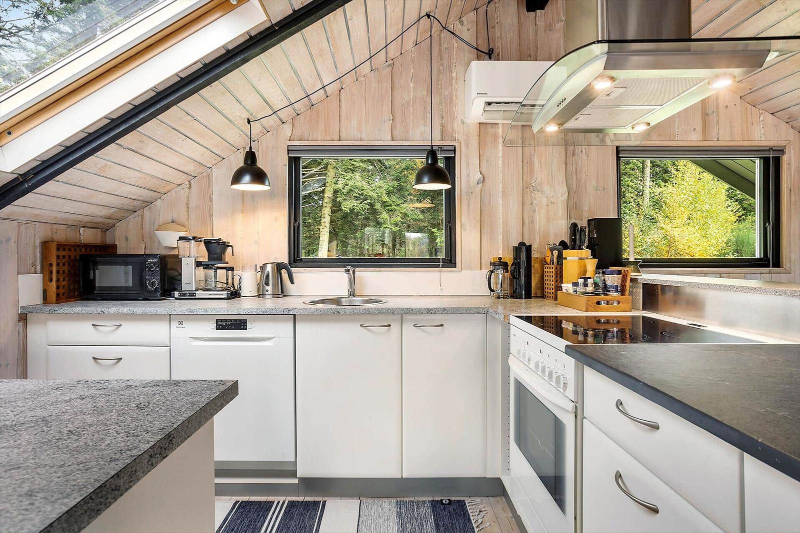 Kitchen with white cabinets, stone countertops, and view of forest.