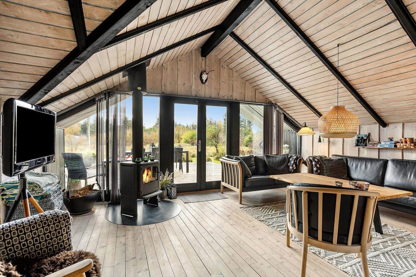 Living room with wooden floor, fireplace, and large window view of garden.