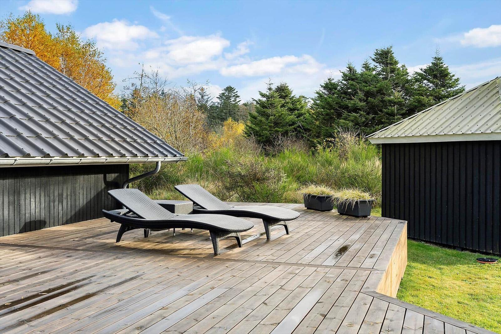 Deck with two loungers and view of forest and sky.