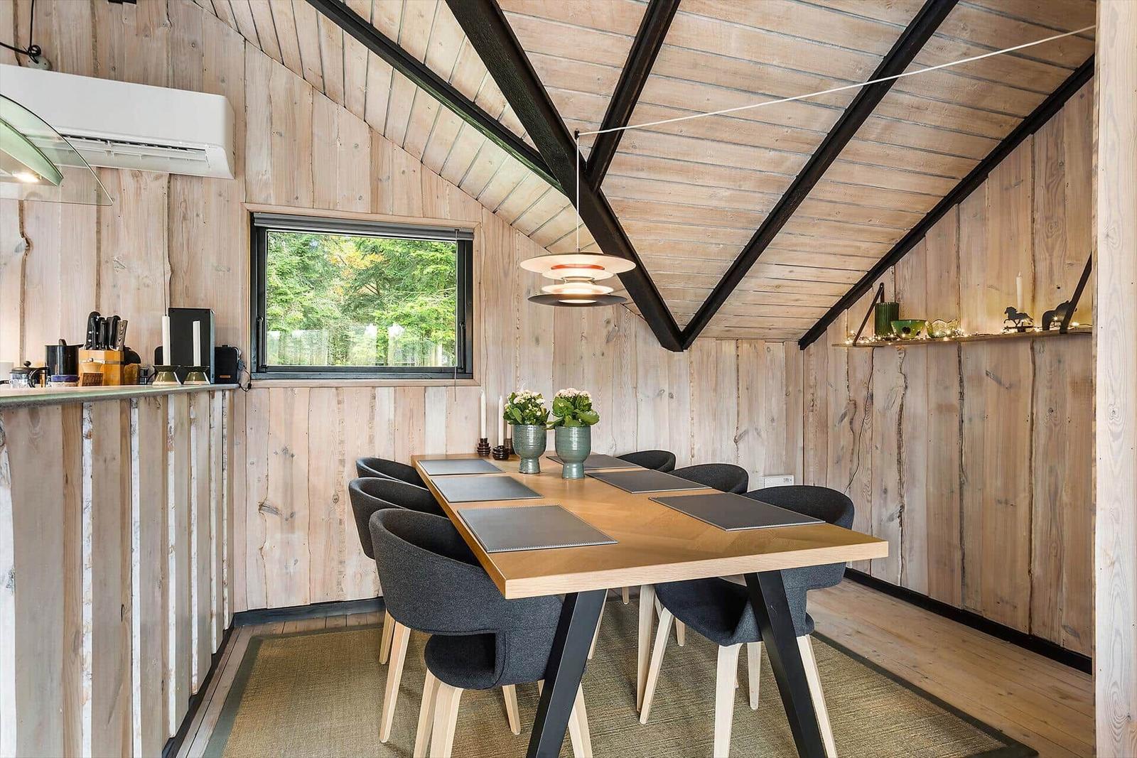 Dining area with wooden walls and table for six people.