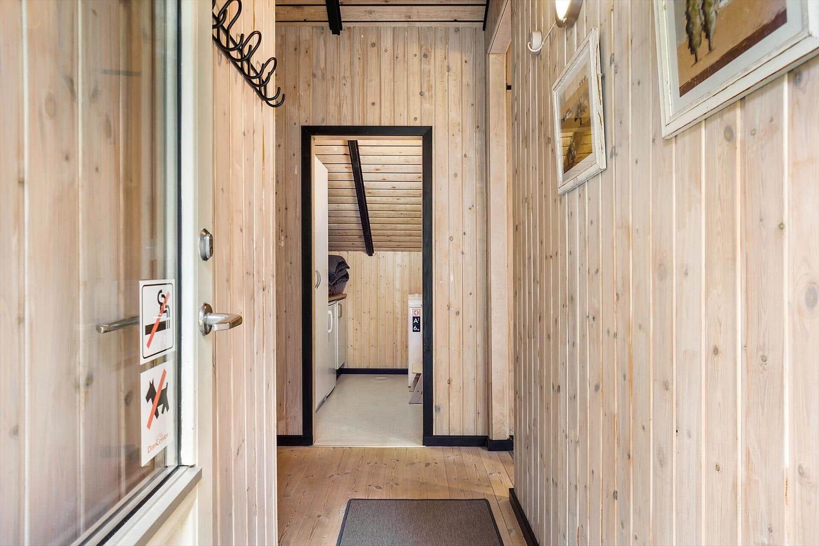 Wood-paneled entryway with pictures and door to the bathroom.