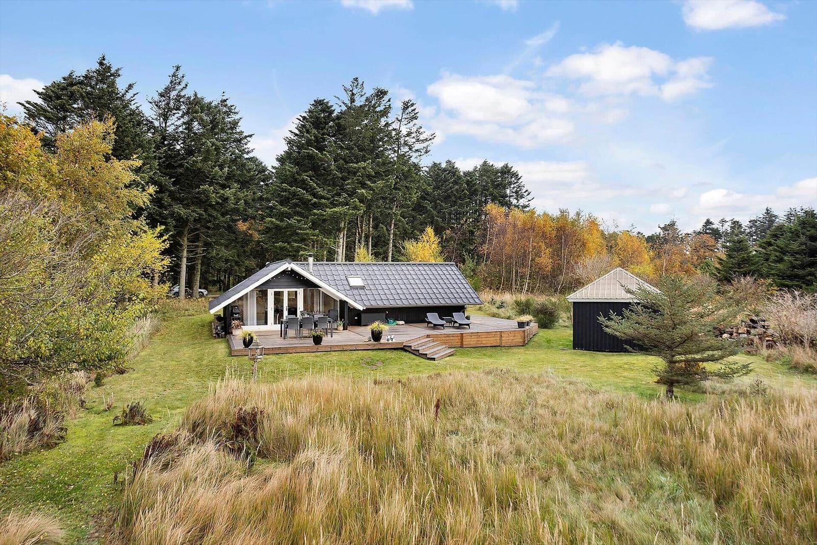 A house with terrace, garden, and forest in the background.