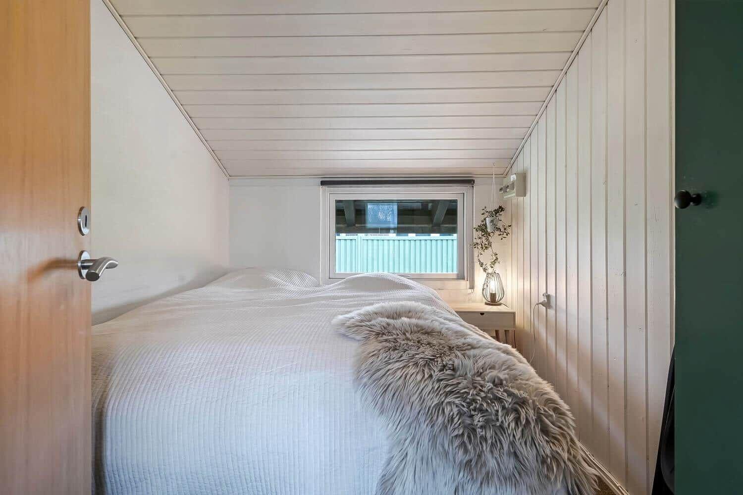 Schlafzimmer mit Bett, Fenster und Nachttisch