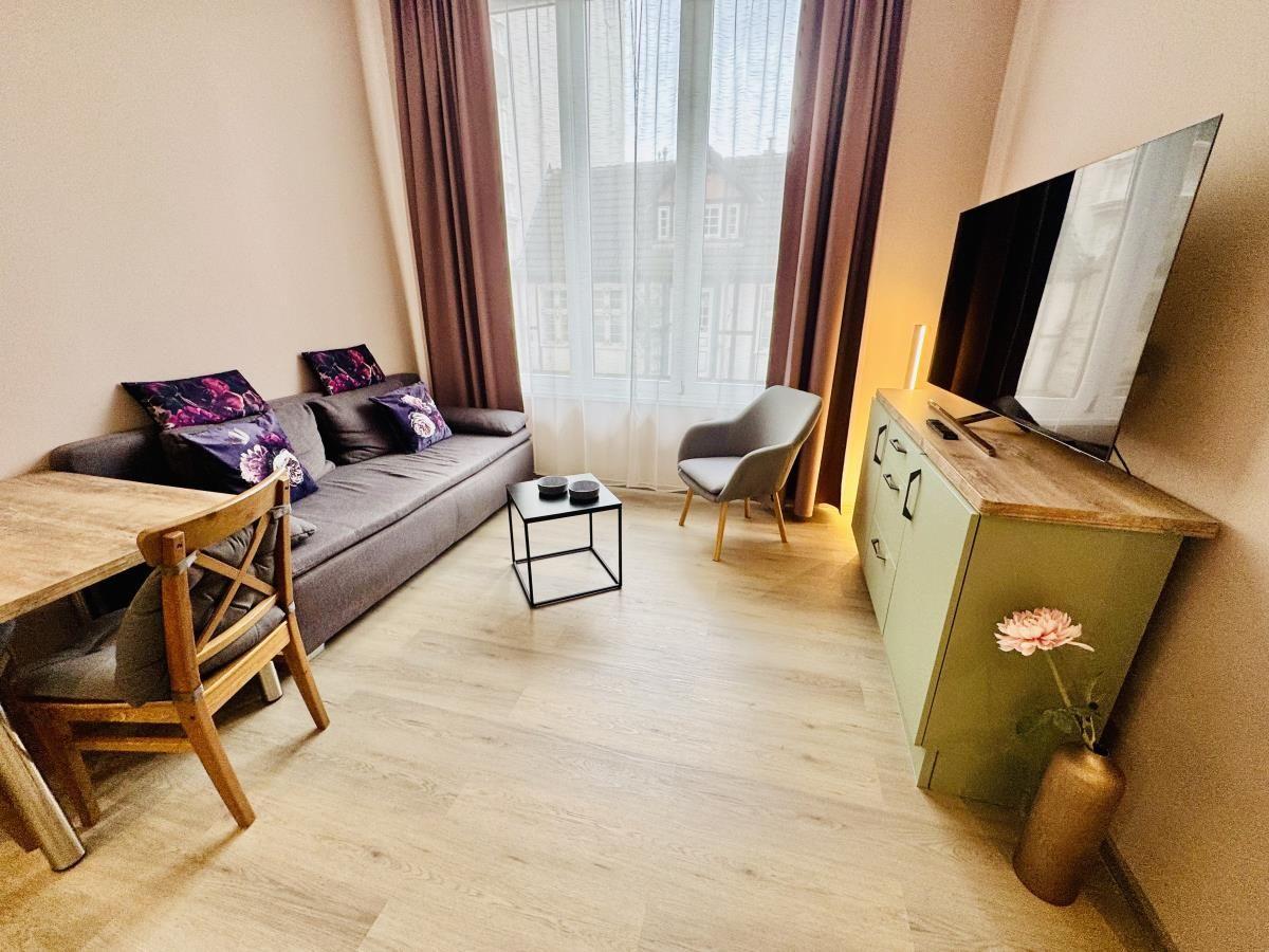 Wohnraum mit Sofa, Tisch, Stuhl und TV. Fenster mit Vorhängen.