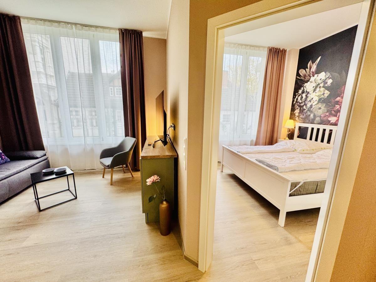 Wohnzimmer mit Sofa und Schlafzimmer mit Bett und Wandbild.