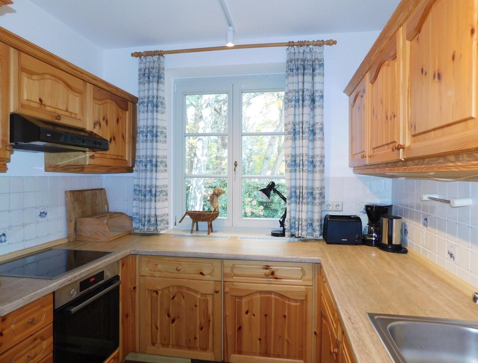 Küche mit Holzschränken, Fenster und Arbeitsfläche