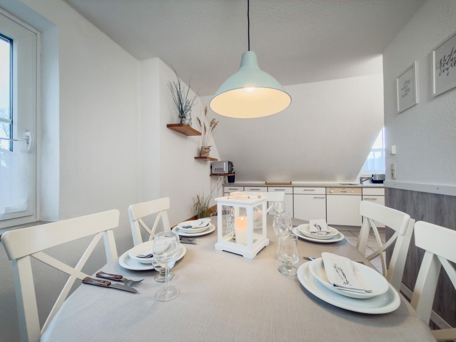 Esstisch mit Stühlen, Lampe und Kerzenhalter im Essbereich.