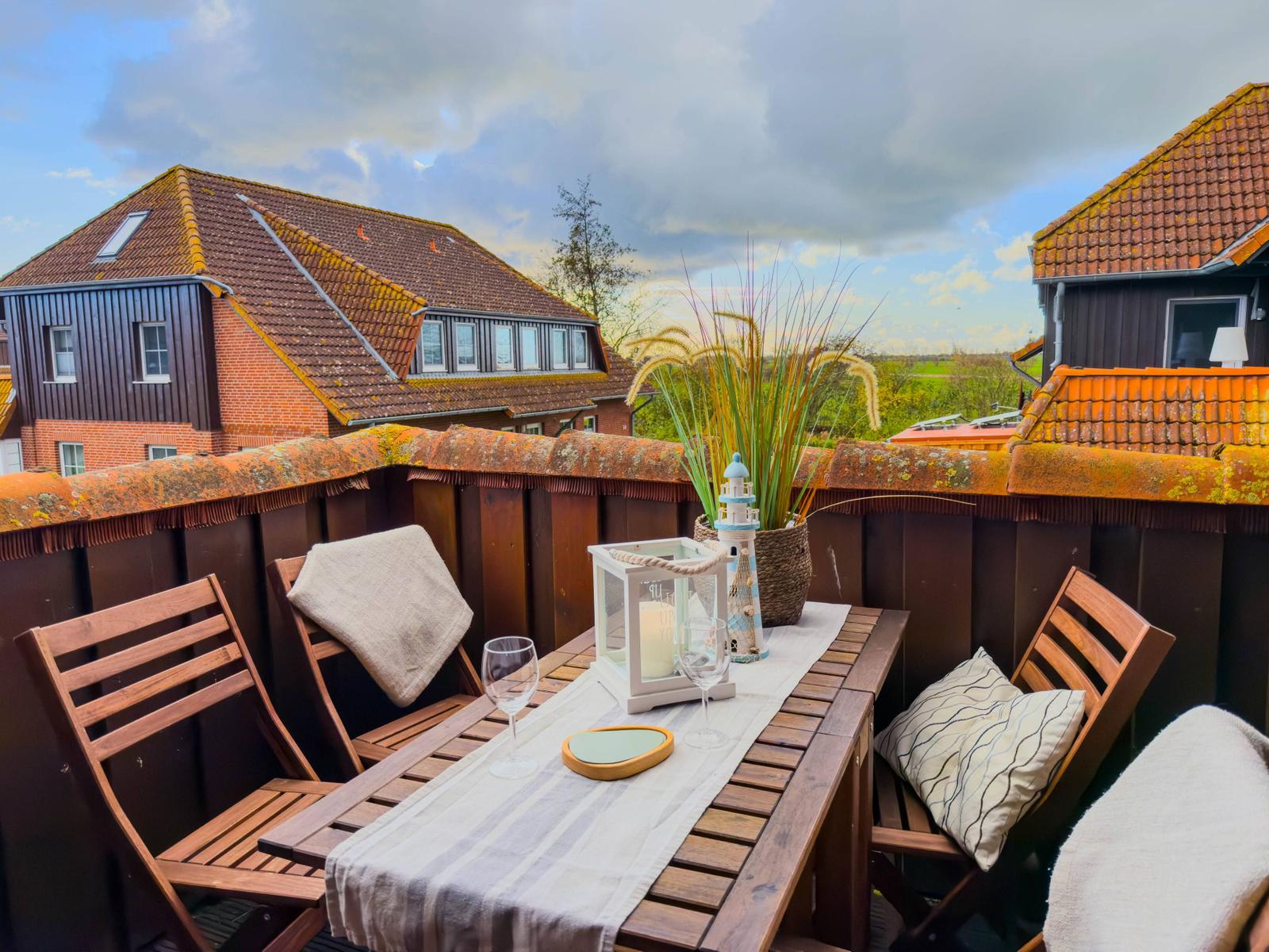 Terrasse mit Tisch, Stühlen und Blick auf Dächer.