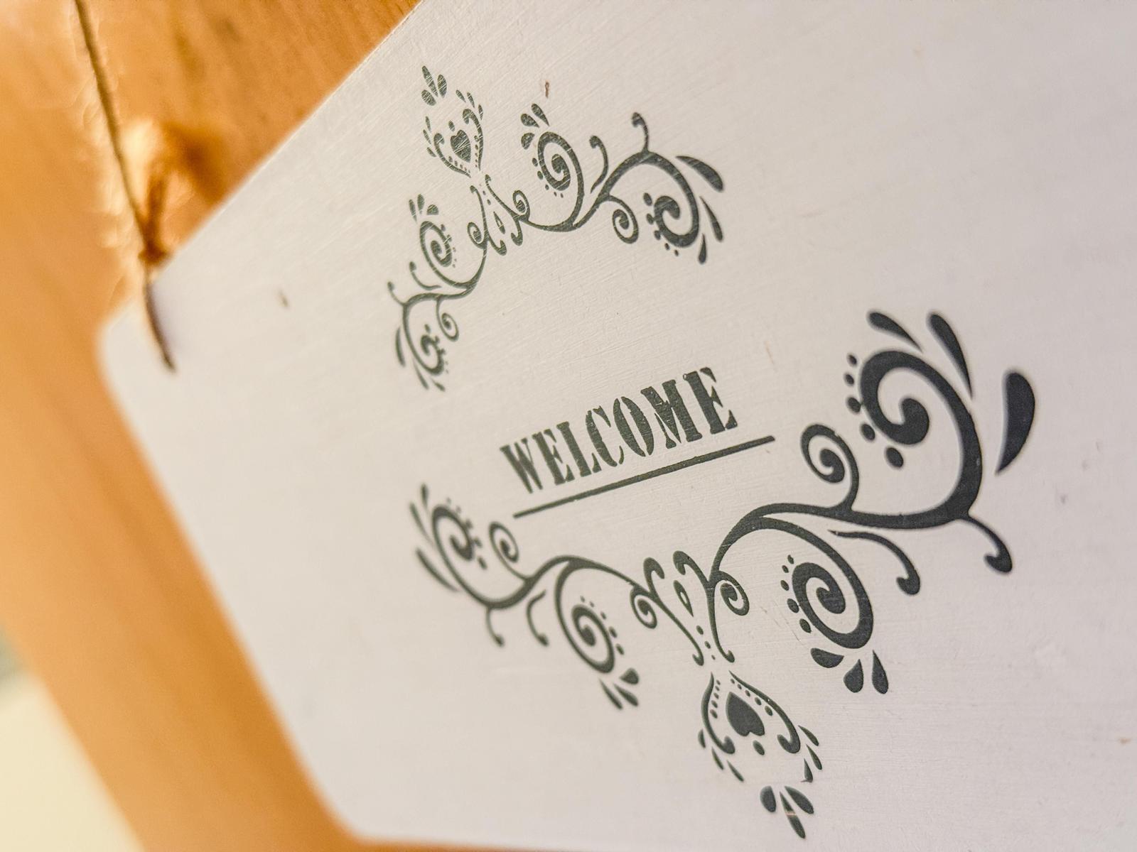 Willkommensschild mit floraler Verzierung an der Tür