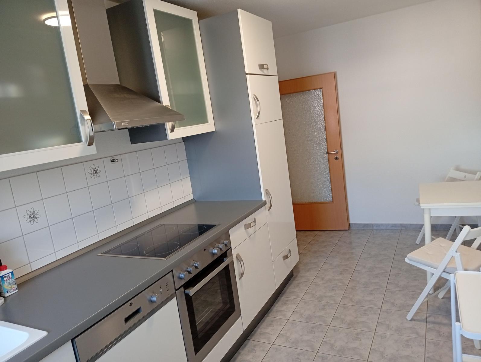 Küche mit Kochfeld, Ofen und Essbereich mit Tisch und Stühlen.