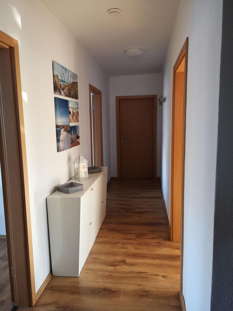 Flur mit Holzboden, weißen Wänden und Bildern an der Wand.