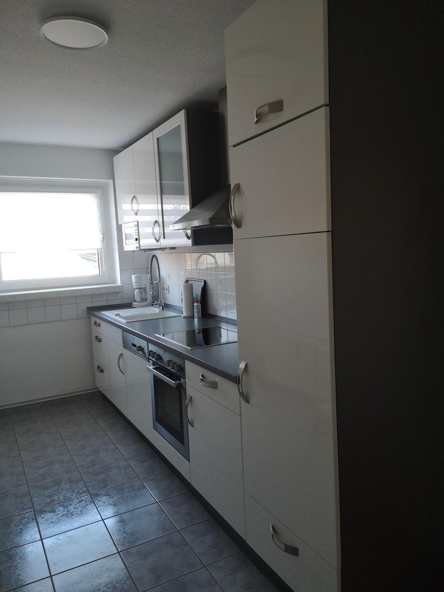 Küche mit weißen Schränken, Arbeitsplatte und Fenster.