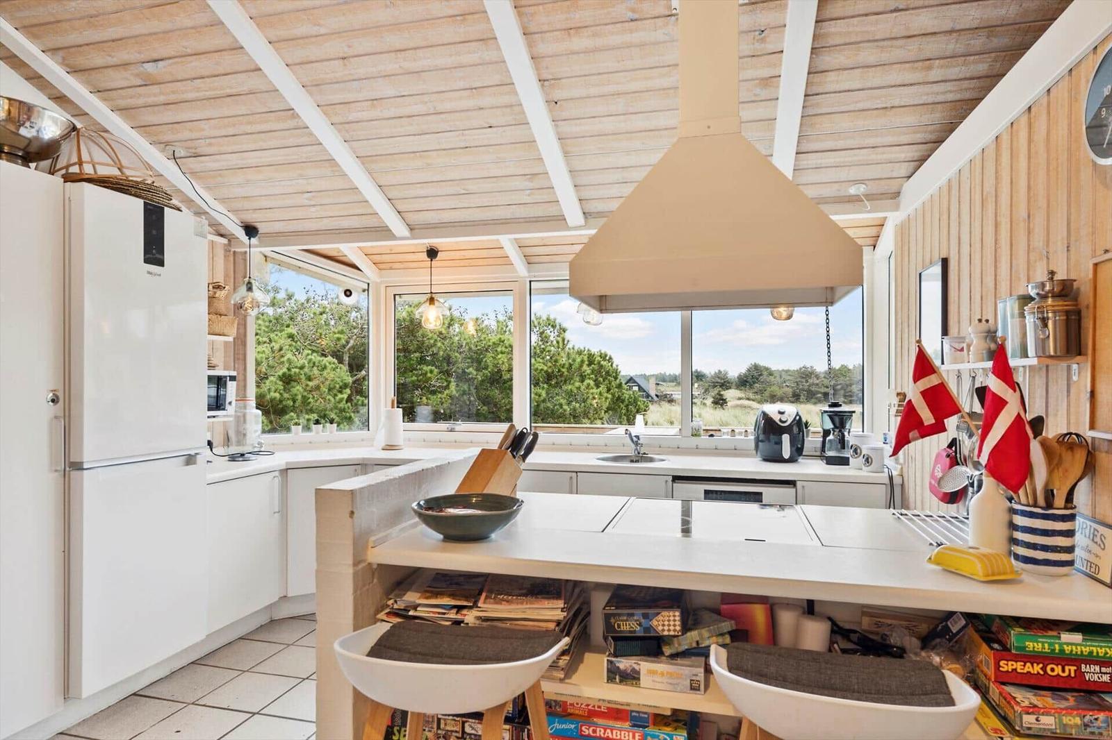 Kitchen with wooden ceiling, large windows, and kitchen island with games.