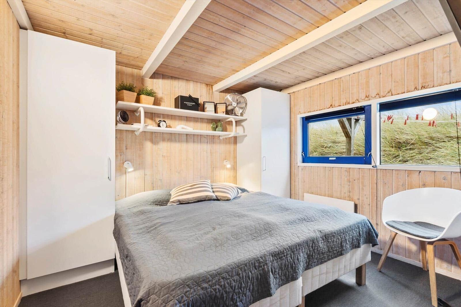 Bedroom with bed, wardrobe, and windows overlooking dunes.