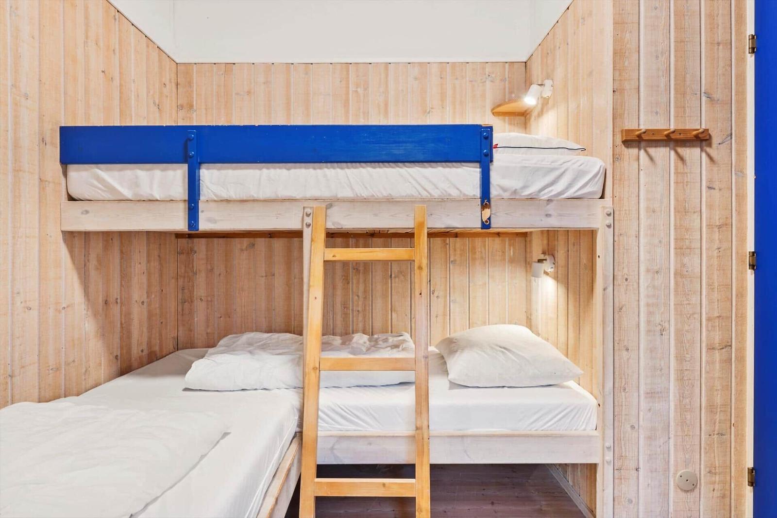 Room with bunk bed, wooden walls, and bedside lamps.