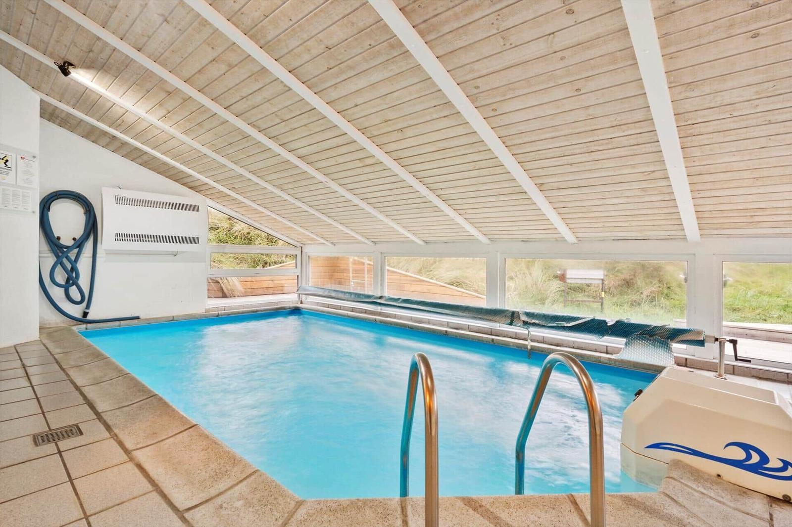 Indoor pool with wooden ceiling and windows to the outside.