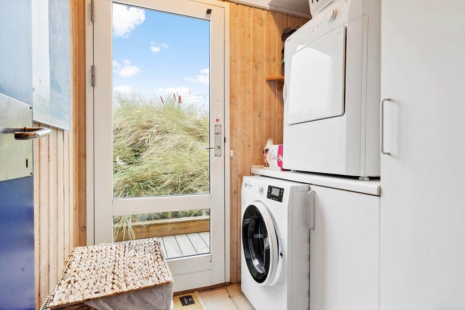 Laundry room with washing machine and dryer. Entrance to terrace with dune view.