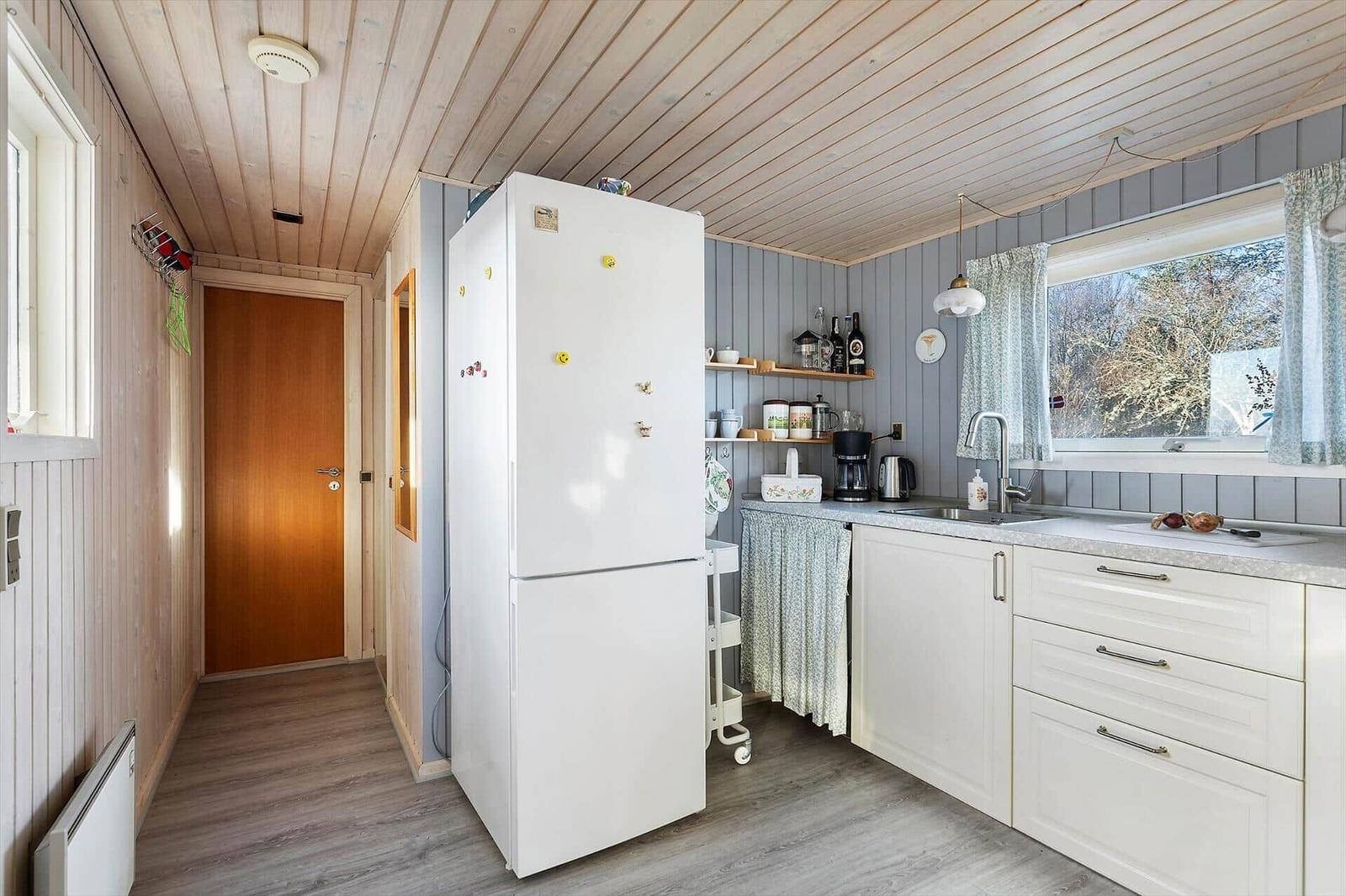 Küche mit weißer Kühlschrank, Arbeitsfläche und Fenster.