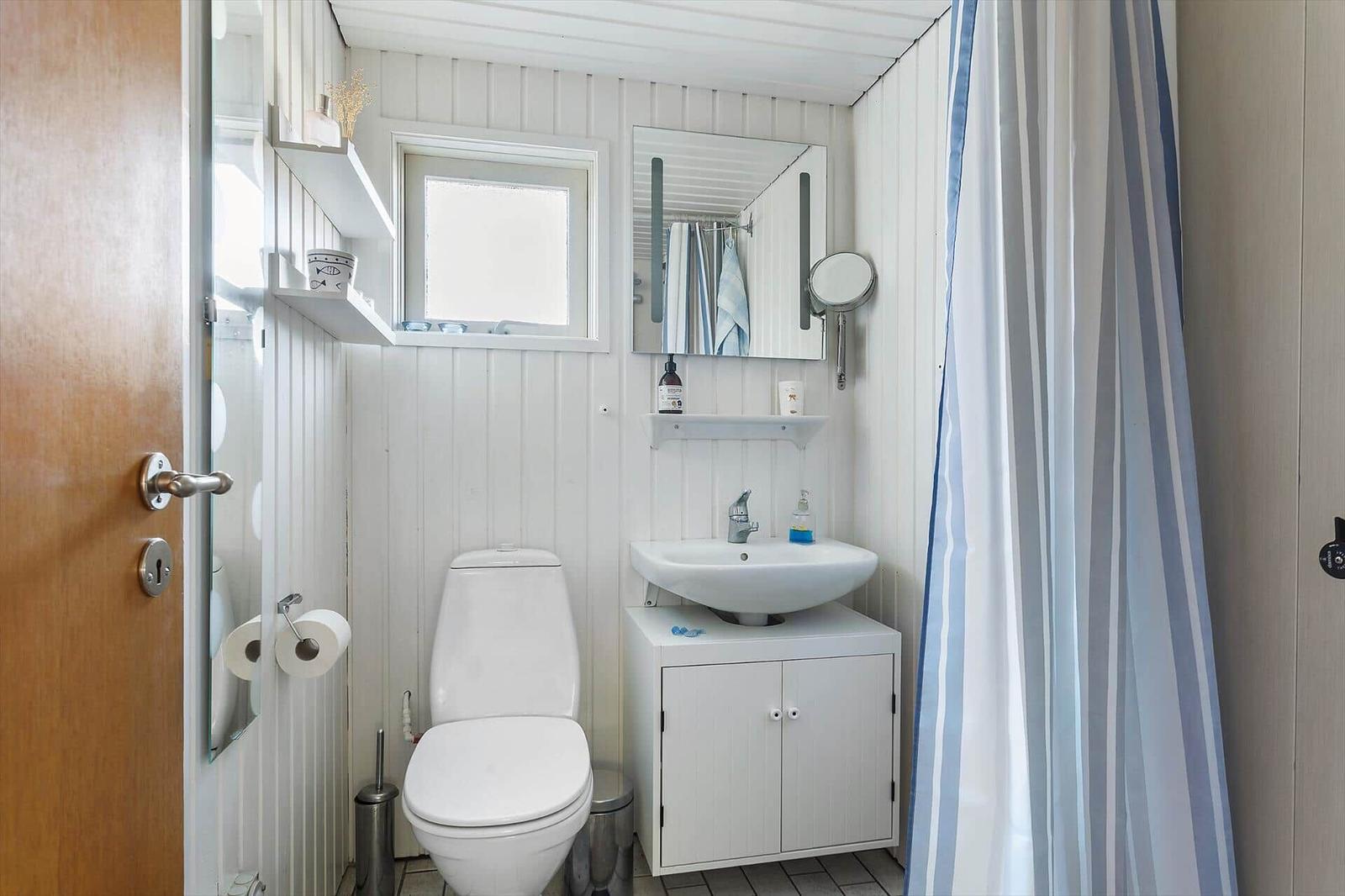 Badezimmer mit Toilette, Waschbecken und Duschvorhang.
