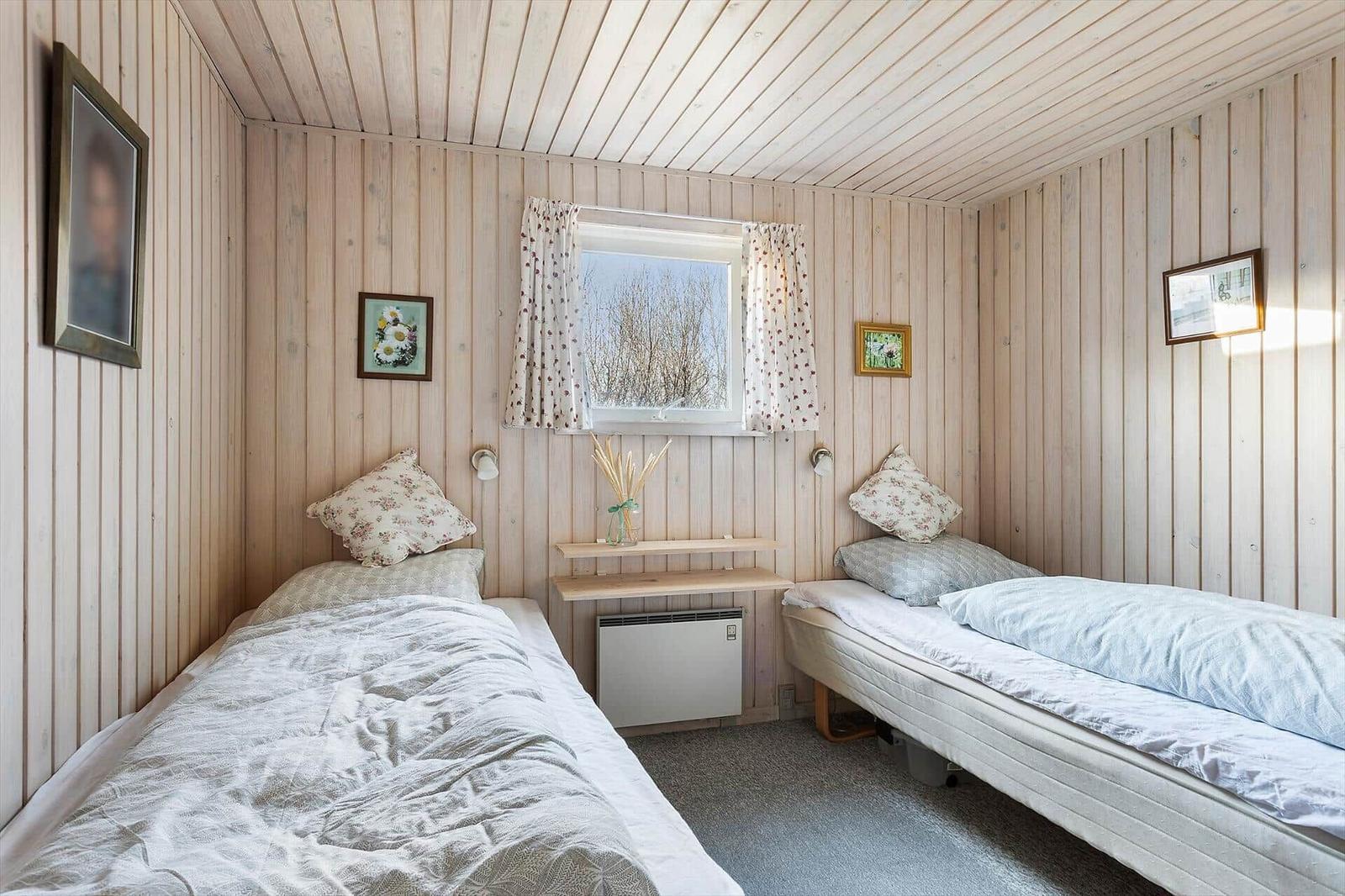 Zwei Betten mit Bettwäsche, Holzwand und Fenster mit Vorhängen.