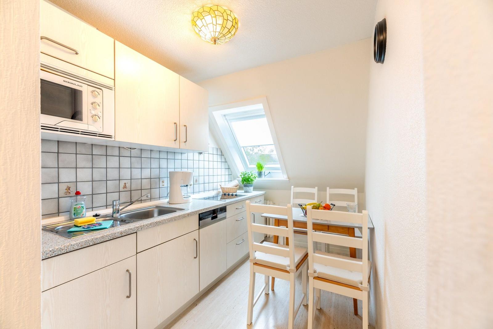 Küche mit Essbereich, Dachfenster und hellen Schränken.