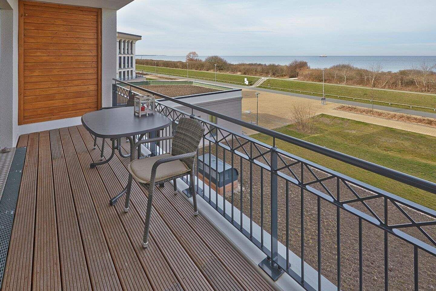 Terrasse mit Tisch und Stuhl, Blick auf Strand und Meer.