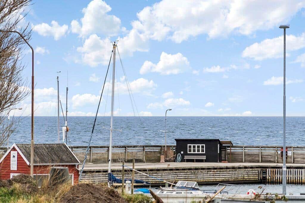 Hafen mit Booten und Blick auf das Meer unter blauem Himmel mit weißen Wolken.