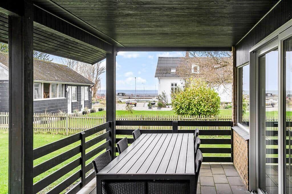 Terrasse mit Tisch und Stühlen, Blick auf Grünfläche und Haus.