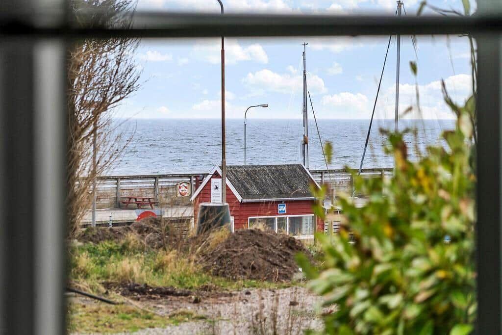 Rotes Haus am Wasser mit Masten und Blick auf See