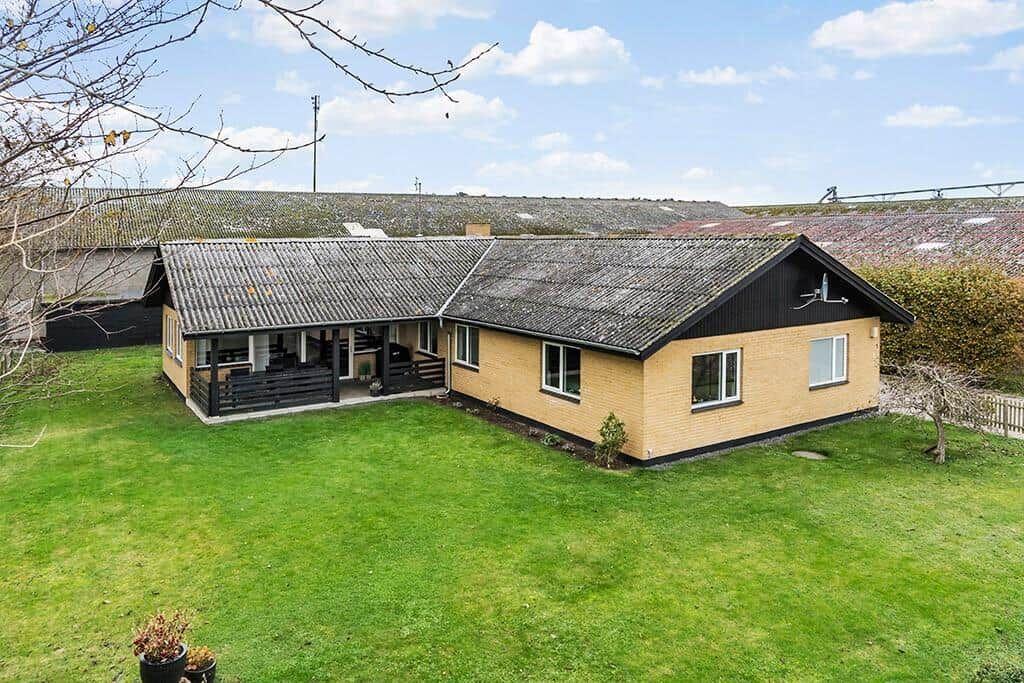 Ein Haus mit gelbem Stein und schwarzem Dach auf grünem Grund.