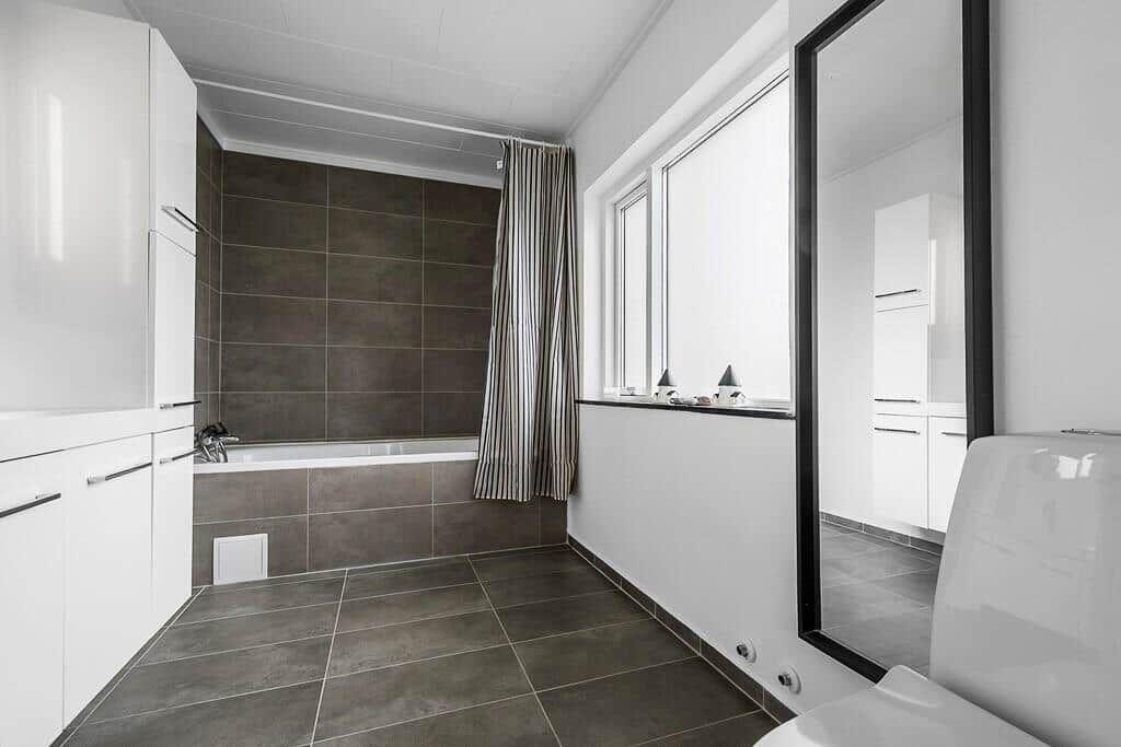 Badezimmer mit Badewanne, Fenster und Spiegel.