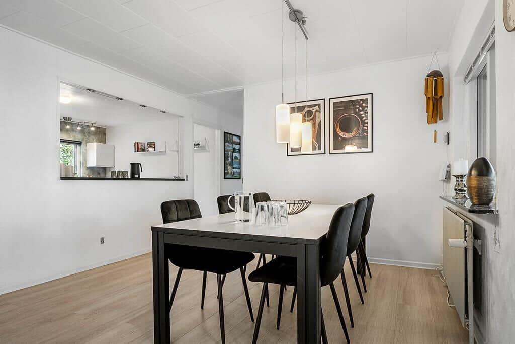 Esszimmer mit Tisch, Stühlen und Küchenbereich im Hintergrund.